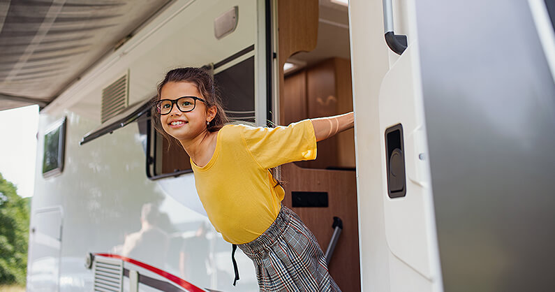 Smiling young girl looking out of caravan